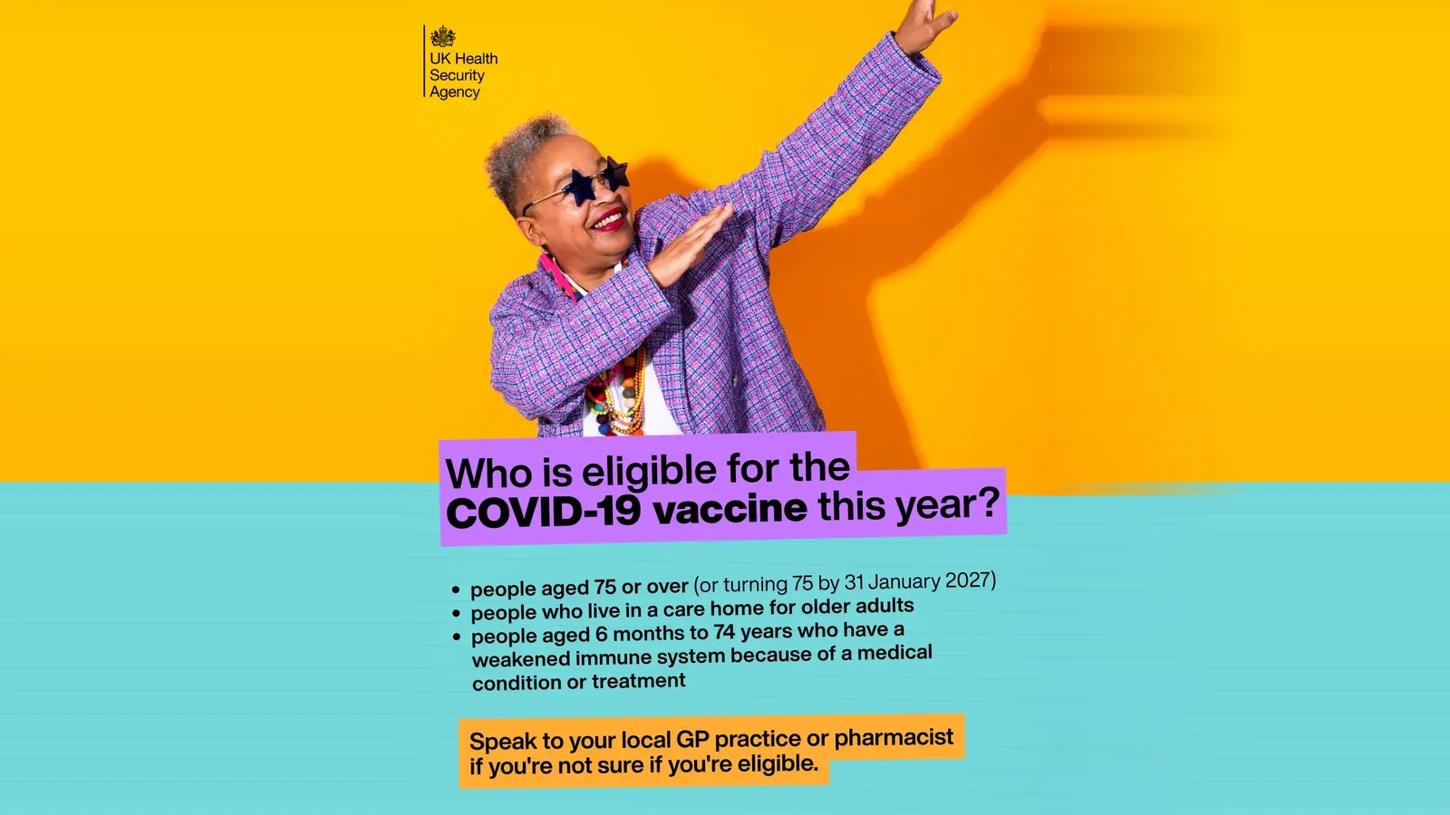 UK Health Security Agency poster of a smiling older woman in star-shaped sunglasses and a purple checked jacket striking a dance pose against a yellow wall, above the question 'Who is eligible for the COVID-19 vaccine this year?' listing people aged 75 or over, care home residents and people with a weakened immune system — who can get a covid booster