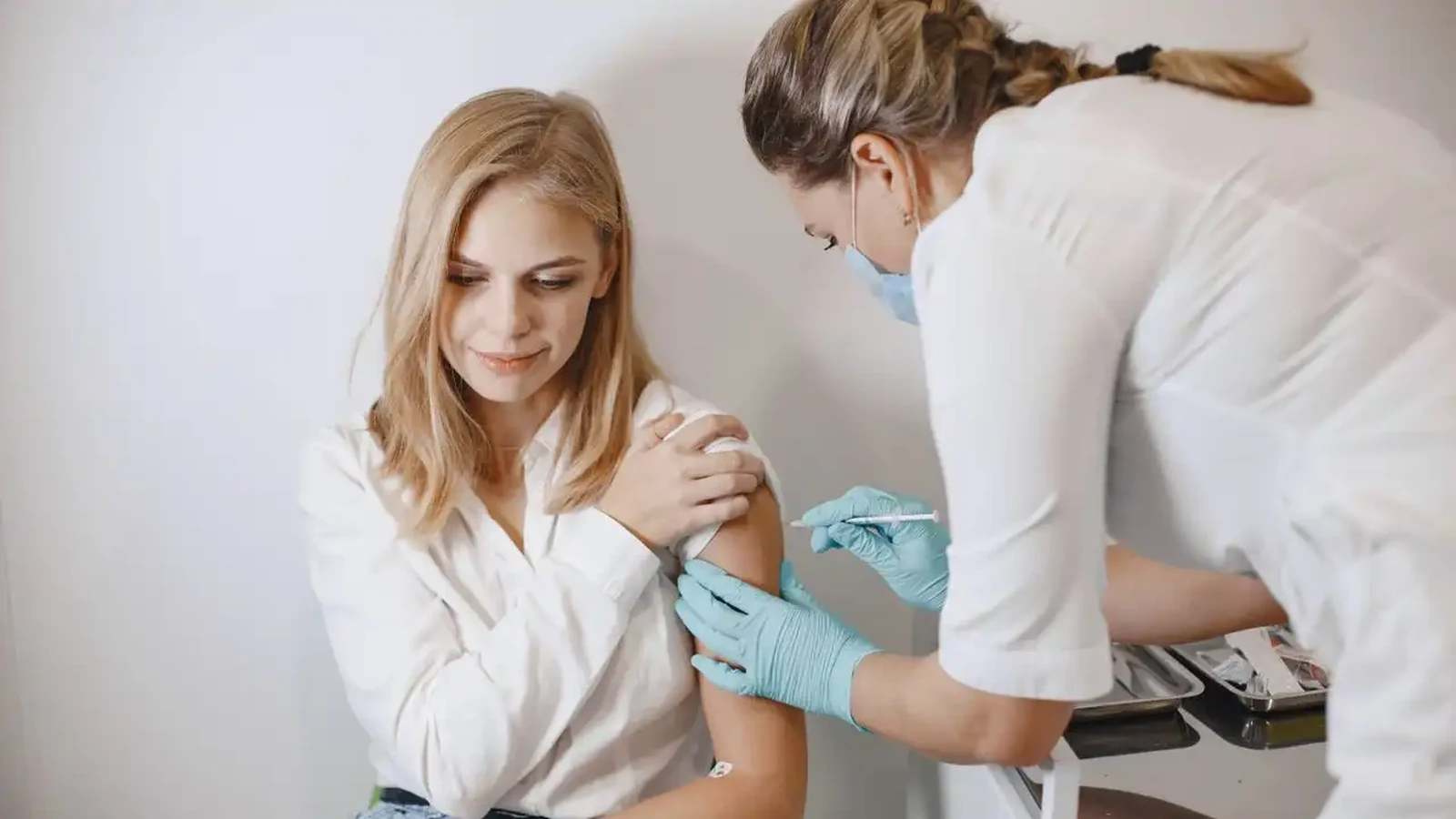 Pharmacist giving a flu jab into a seated patient's upper arm at Garner Chemist in Harrow