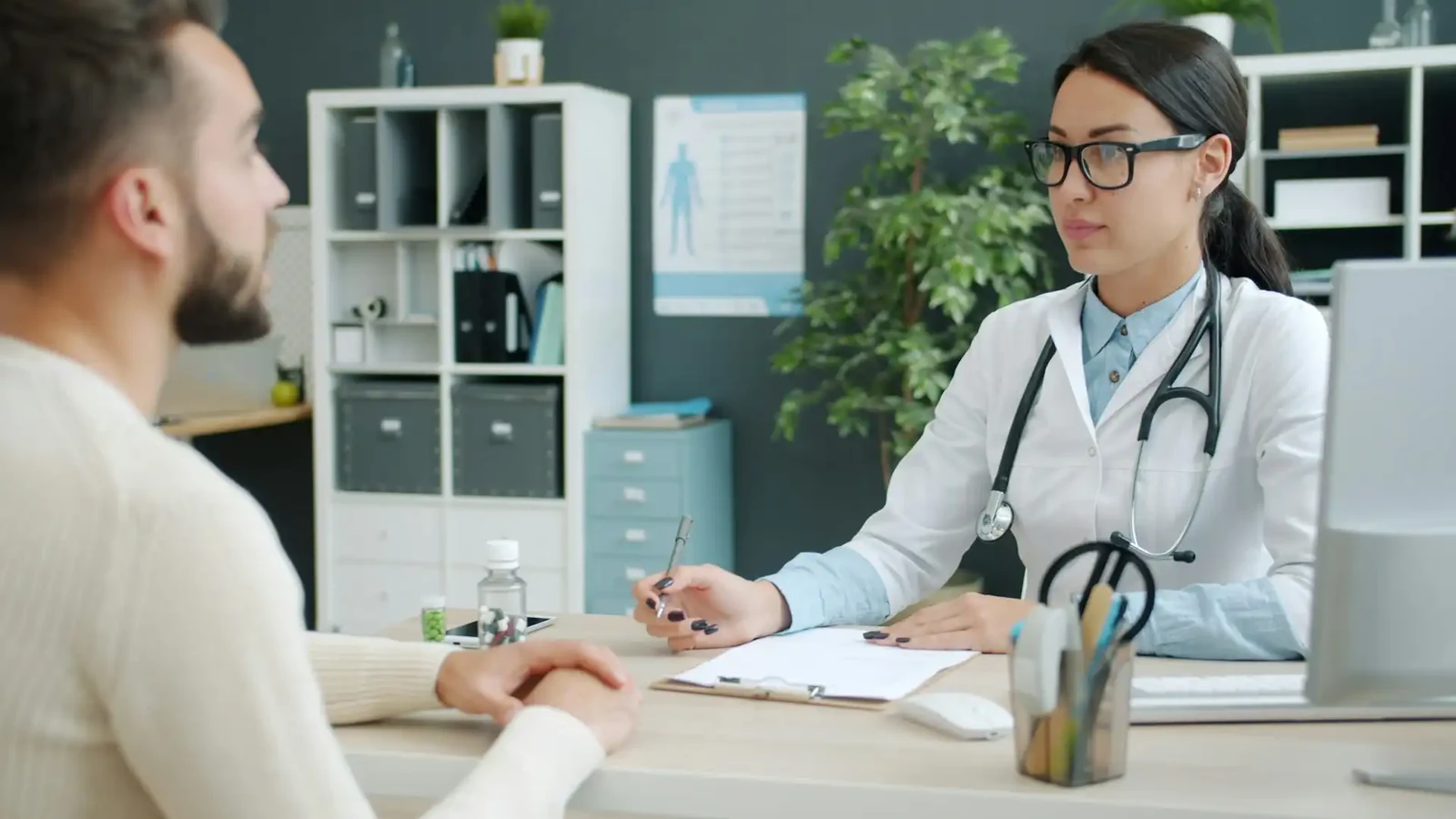 Clinician going through a patient's medicines with him across a consultation desk during a medication review
